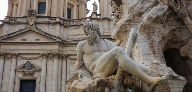 View of the statue representing the River Ganges on the fountain of the Four River in Piazza Navona Rome with the church of St Agnes in Agone in the background