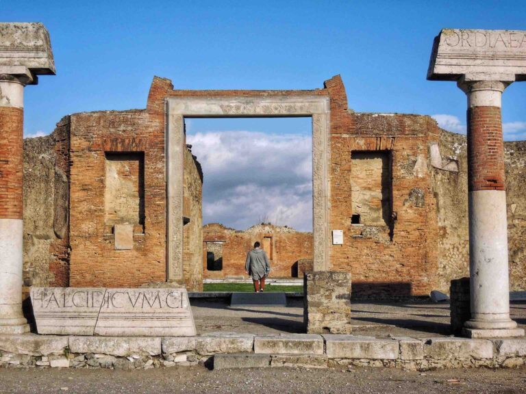 The Forum of Pompeii in Italy with a visitor wandering through the ruins and colonnades